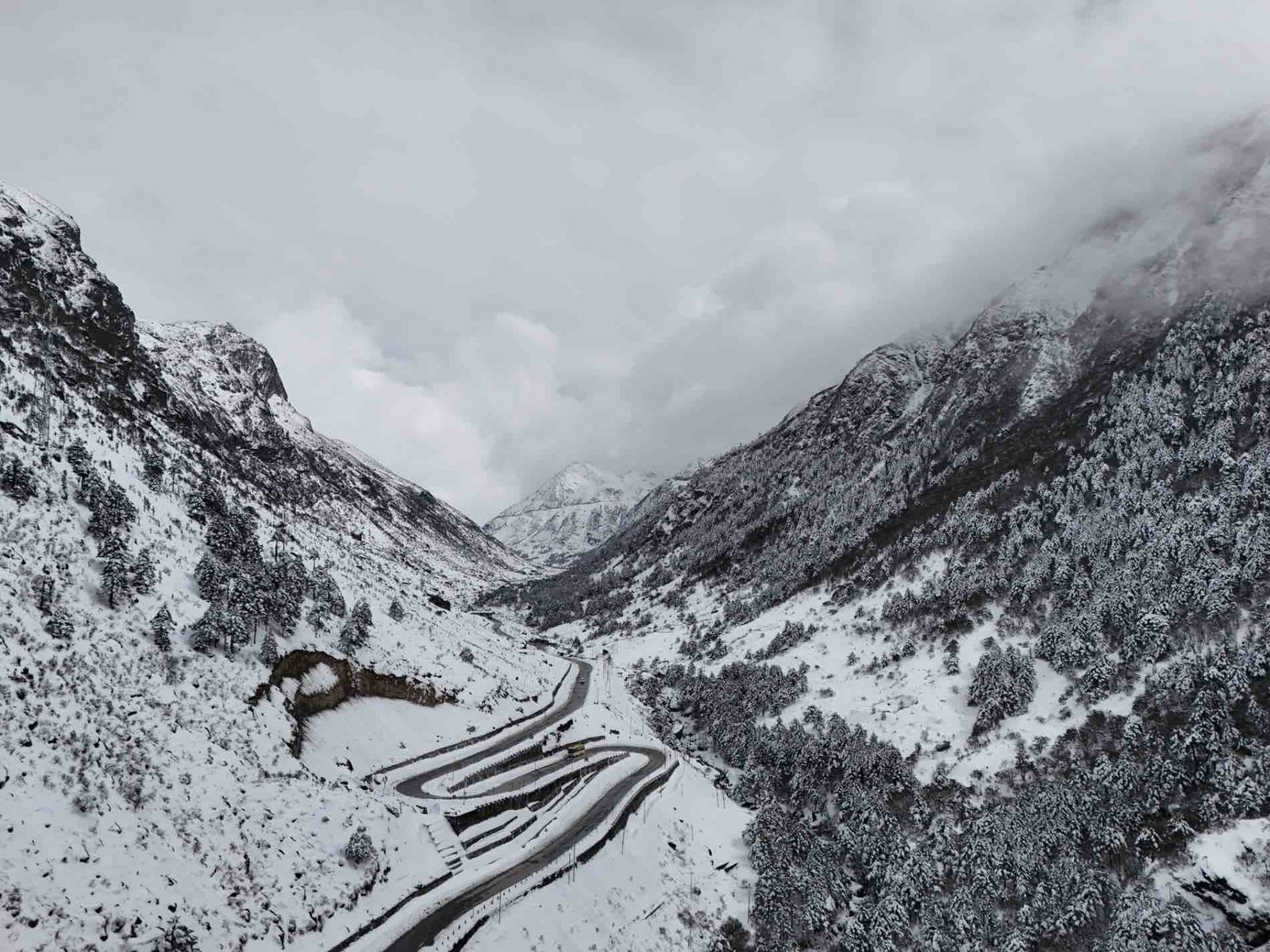 Wild Hill Adventure Winding mountain road through snow-covered Himalayan valleys in winter, featured in the Tawang winter senior citizen tour package by Wild Hill Adventure.