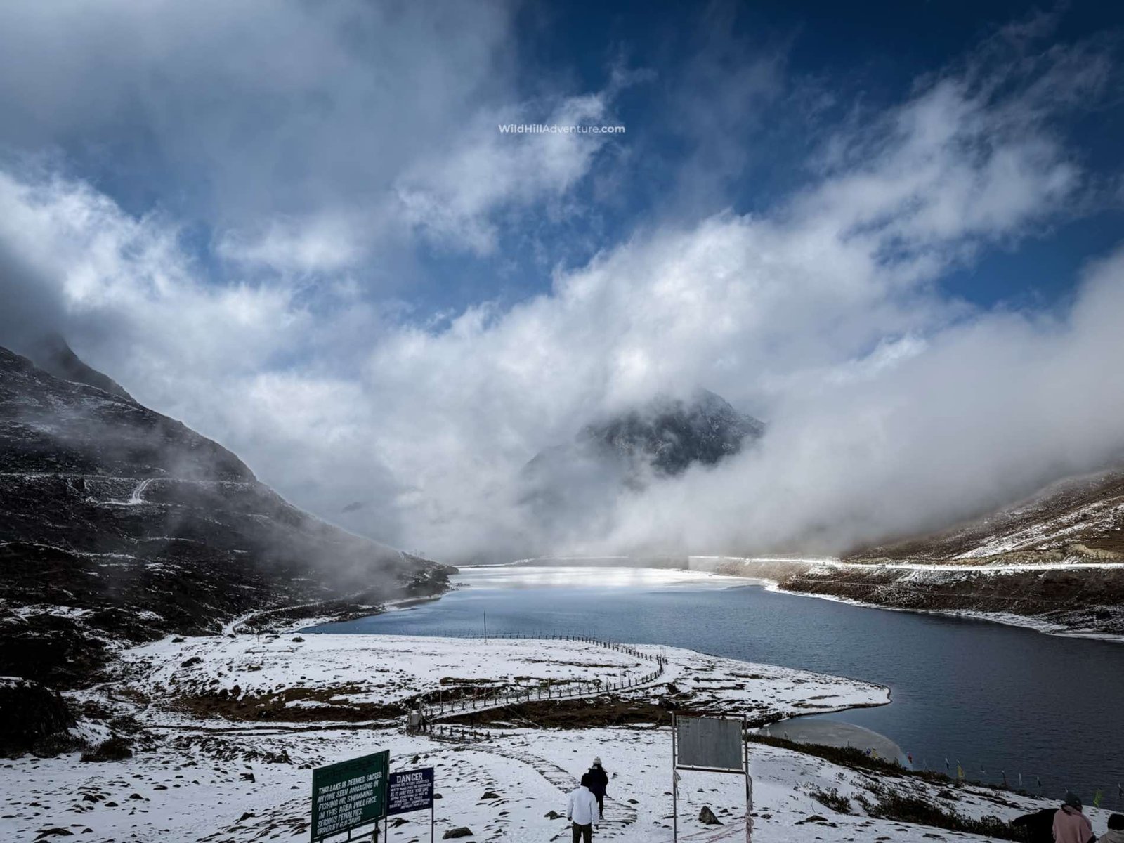 Wild Hill Adventure Snow-covered Himalayan lake surrounded by misty mountains in winter, featured in the Tawang winter senior citizen tour package by Wild Hill Adventure.