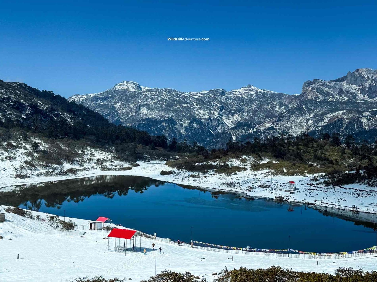 Wild Hill Adventure Tawang Winter Tour Package featuring a snow-covered high-altitude lake surrounded by rugged Himalayan mountains and snowy landscapes in Arunachal Pradesh.