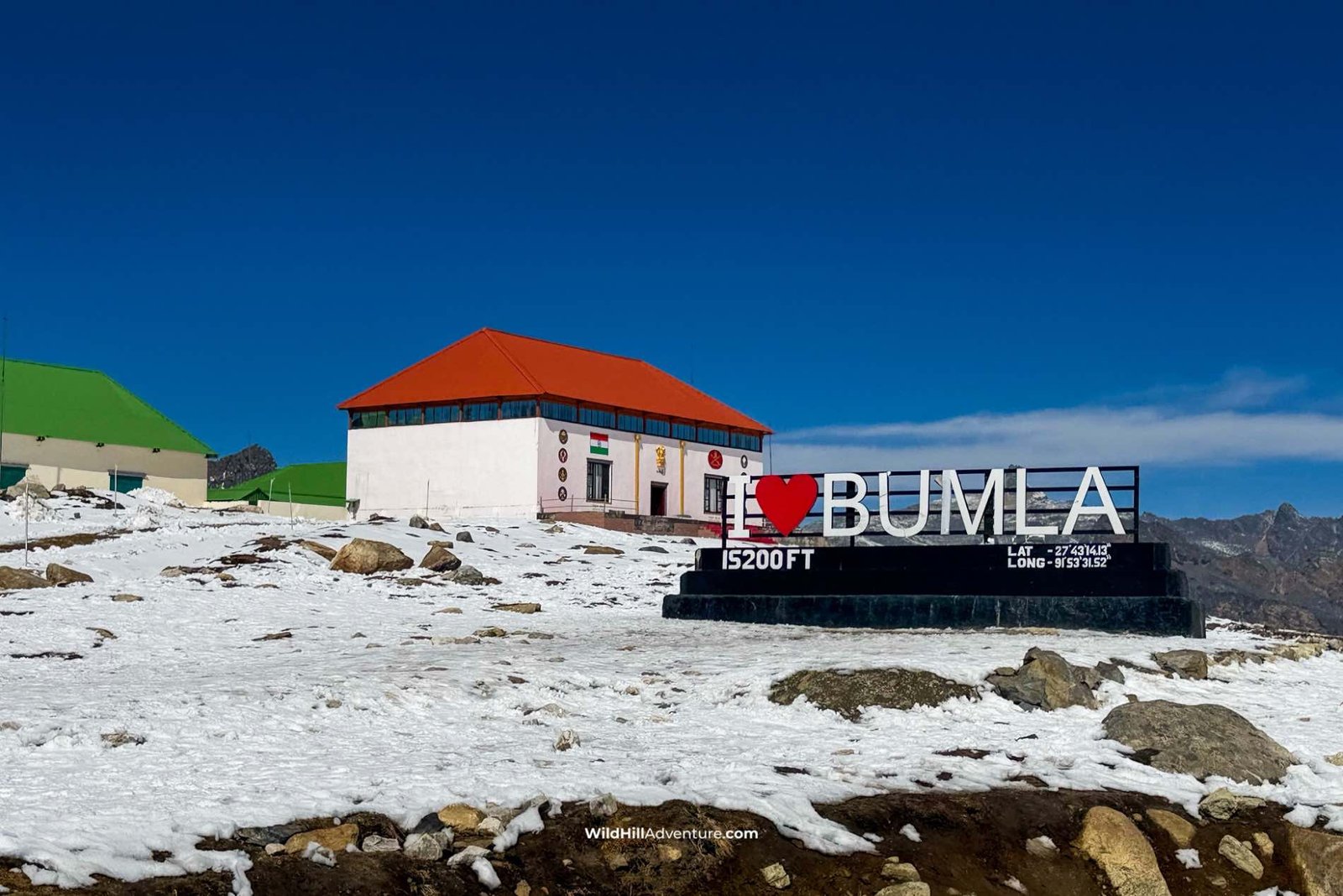 Wild Hill Adventure Snow-covered Bumla Pass in Tawang, Arunachal Pradesh, with the I Love Bumla sign and mountain landscape.